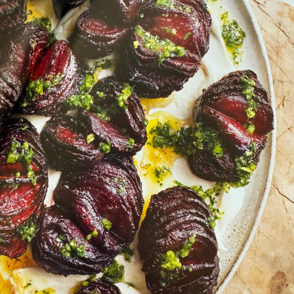 Roasted beets with green herb garnish on a white plate